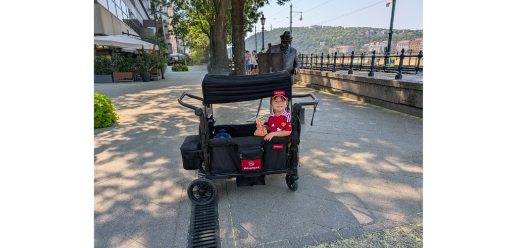 Boy sitting in the Arkonno stroller wagon on a riverside promenade